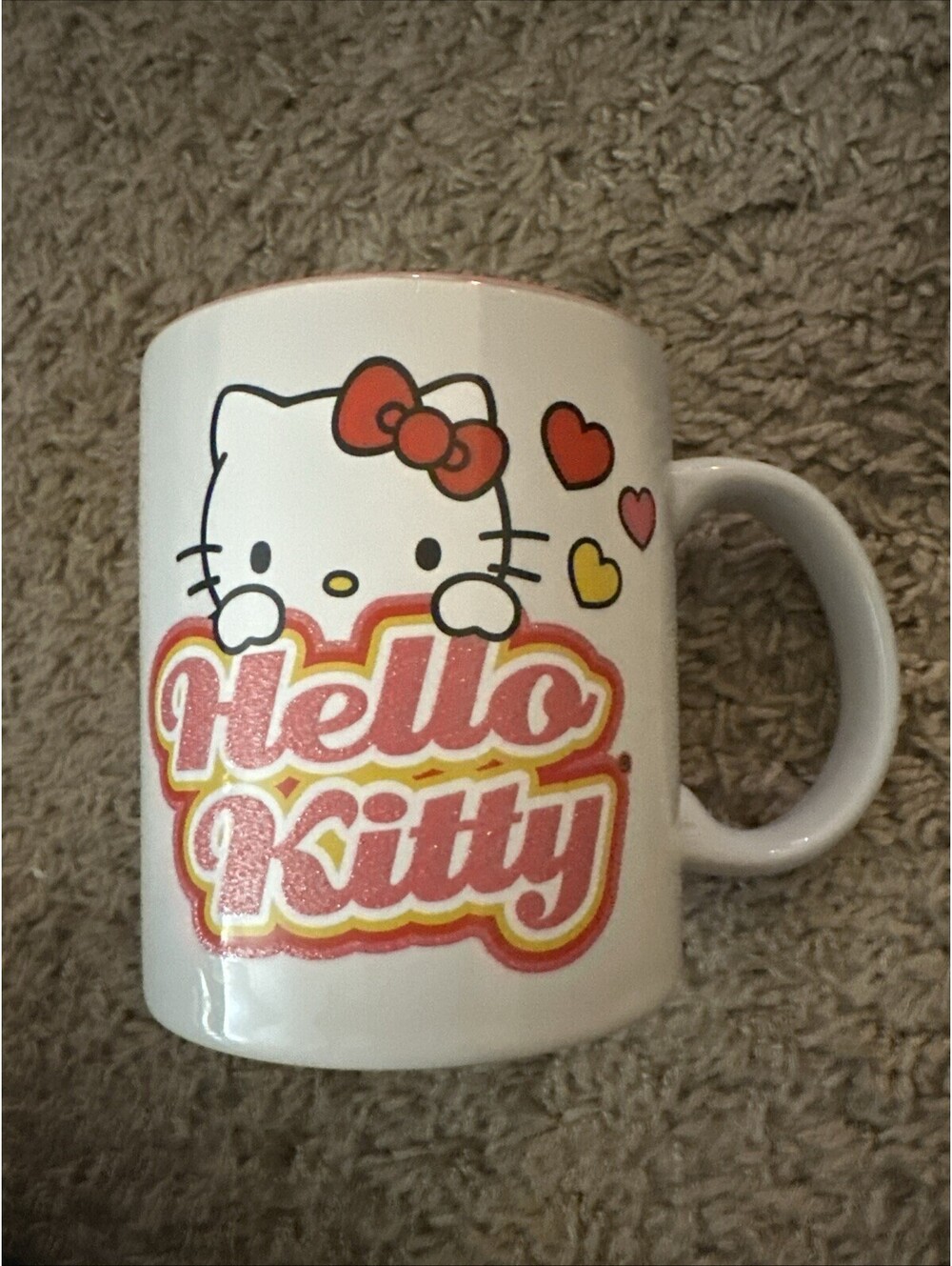 Hello Kitty ceramic mug featuring the character peeking over the "Hello Kitty"